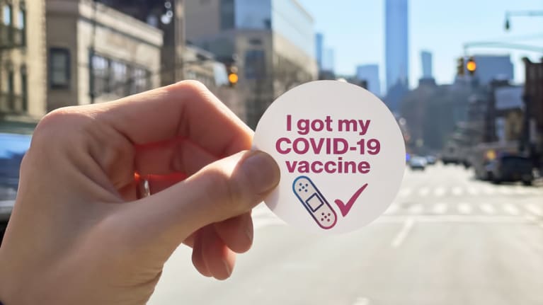 Person holding COVID-19 vaccine sticker