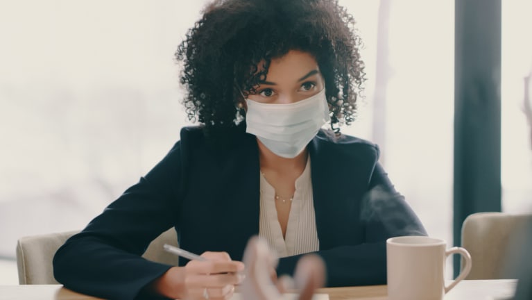  businesswoman wearing a mask while in a meeting
