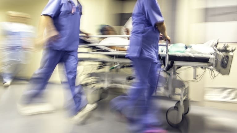 two health care workers rolling someone into emergency care