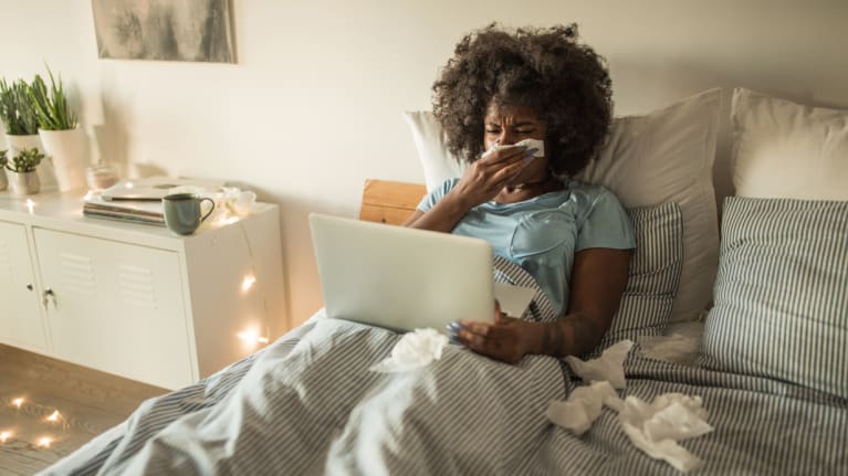 woman sick in bed on laptop