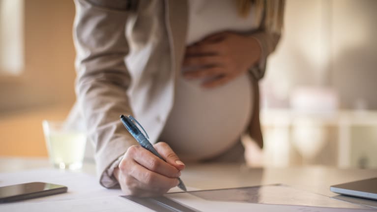 a pregnant woman writing at work