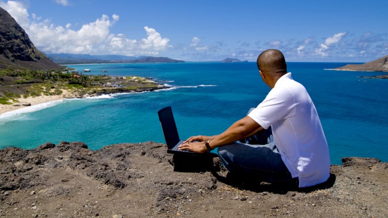 man with laptop on beach in hawaii