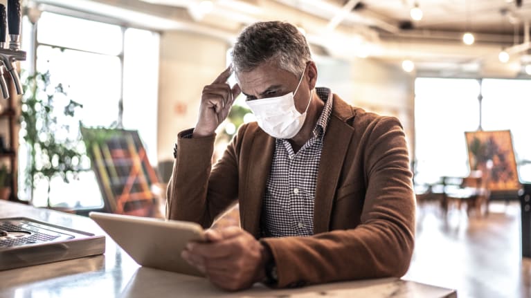 man wearing mask working on laptop