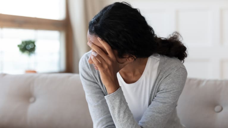 grieving young woman with a hand over her face