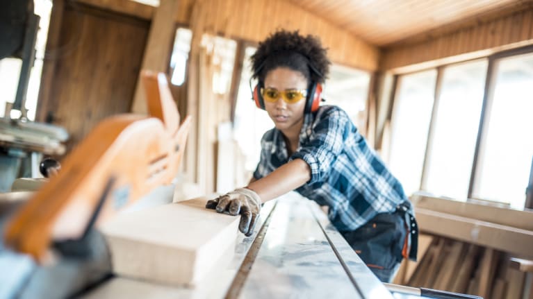 a worker sawing off a block of wood