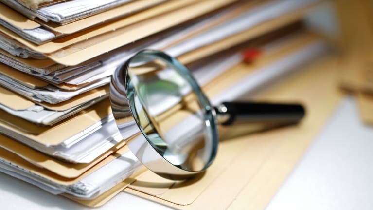 A magnifying glass on a stack of folders