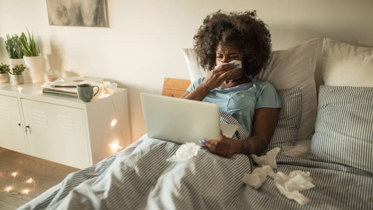 woman sick in bed with laptop