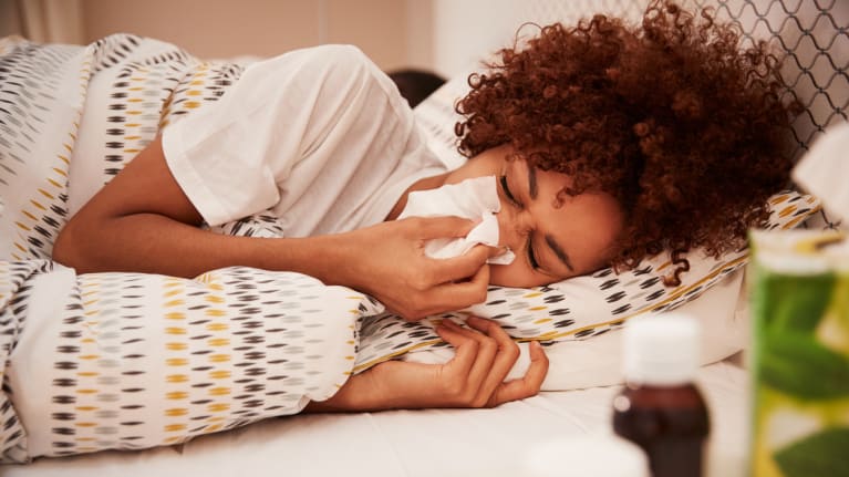 woman sick in bed with tissue