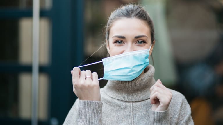 woman taking off a protective face mask