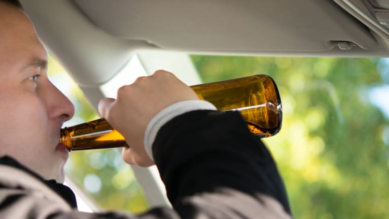 A business professional drinking in his car