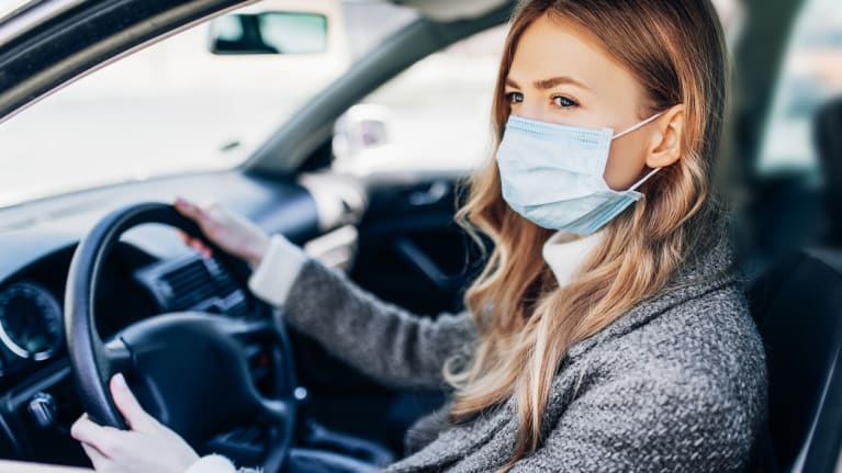 woman wearing mask sitting in car