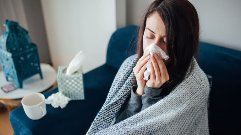 woman at home sick on couch with blanket