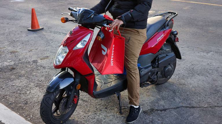 A moped driver about to make a DoorDash delivery