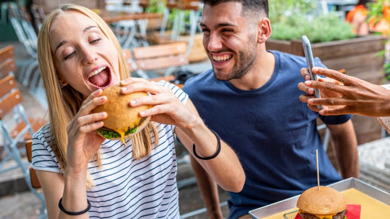 woman eating hamburger with friends