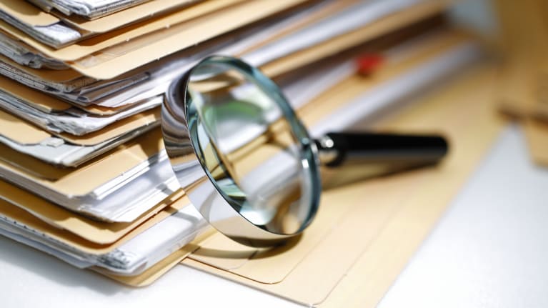a magnifying glass on a stack of folders
