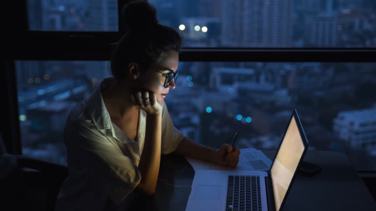 Woman working on laptop in the dark