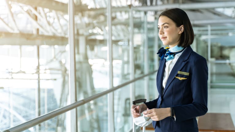Cabin crew member holding mask in her hands