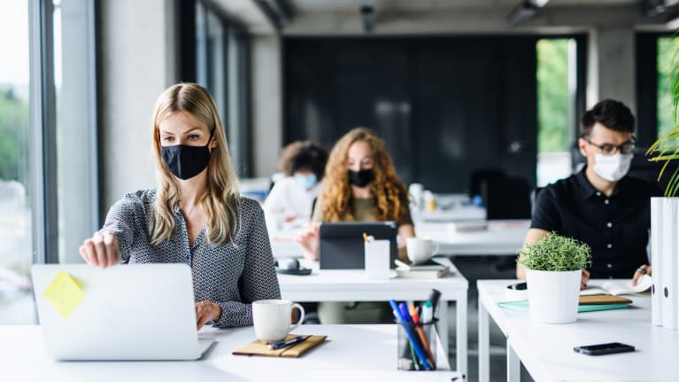 Office workers wearing masks and social distancing