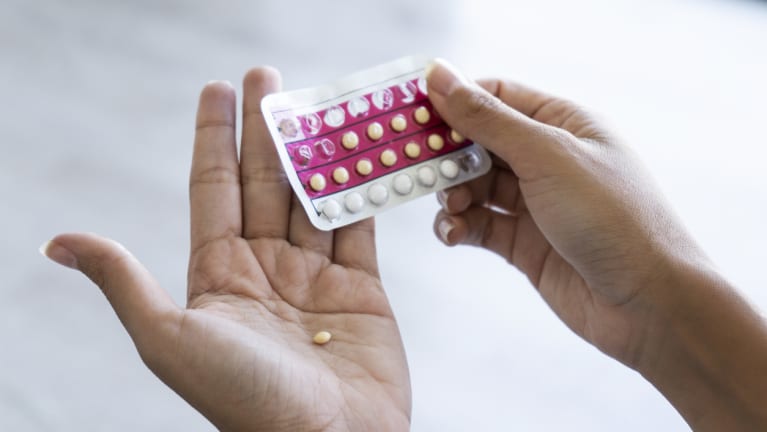 A woman holding birth control pills