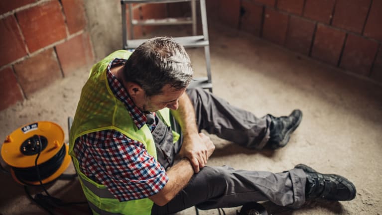 worker holding hurt arm near ladder