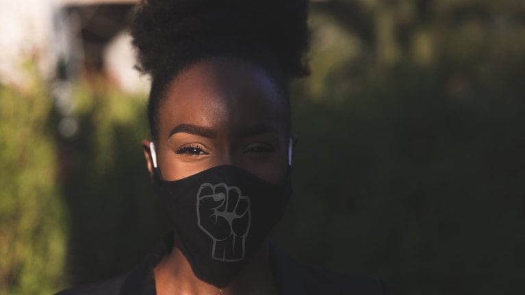 woman wearing facemask with black power symbol