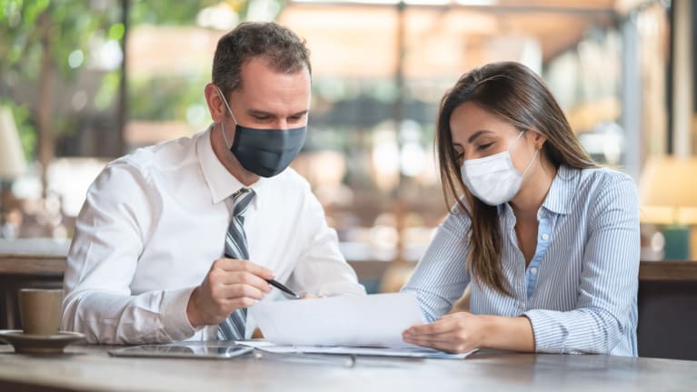 business people reviewing documents and wearing masks