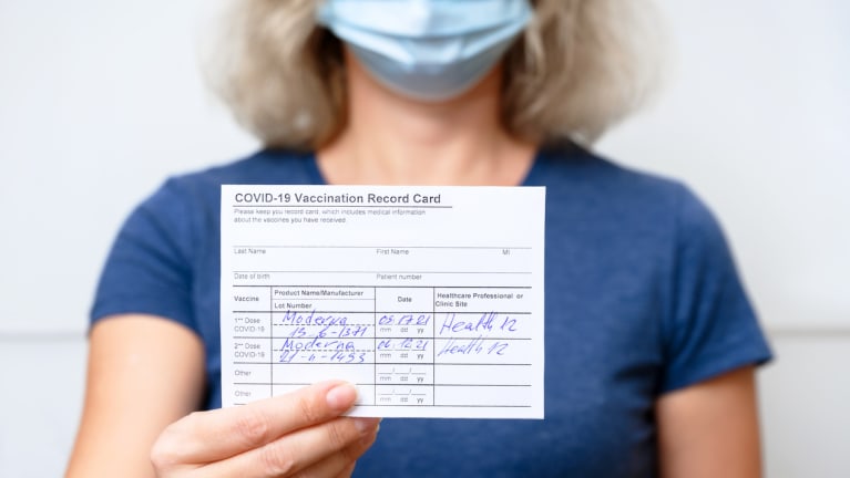 Woman showing COVID-19 Vaccination Record Card