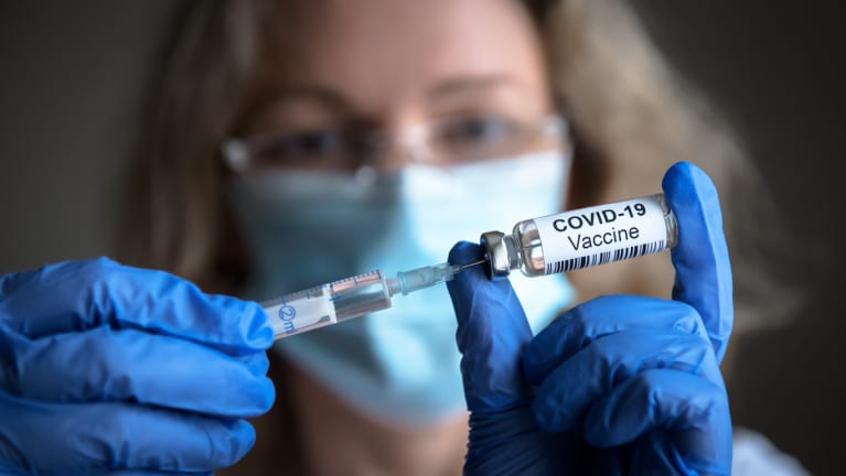 A health care worker administering a COVID-19 vaccine