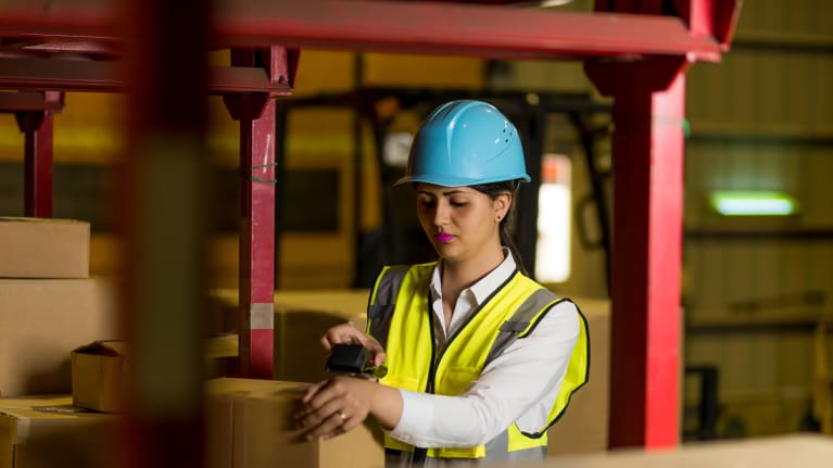 an Indian woman in a hard hat on a factory floor