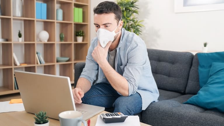 employee wearing face mask selects benefits from his laptop.
