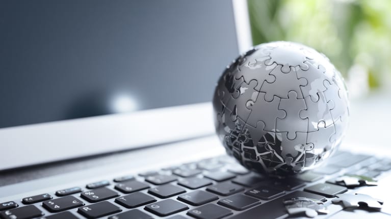 A globe made of puzzle pieces on a laptop&#39;s keyboard