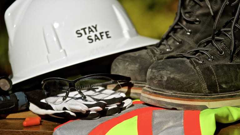 an assortment of personal protective equipment, including a helmet, work boots and safety glasses