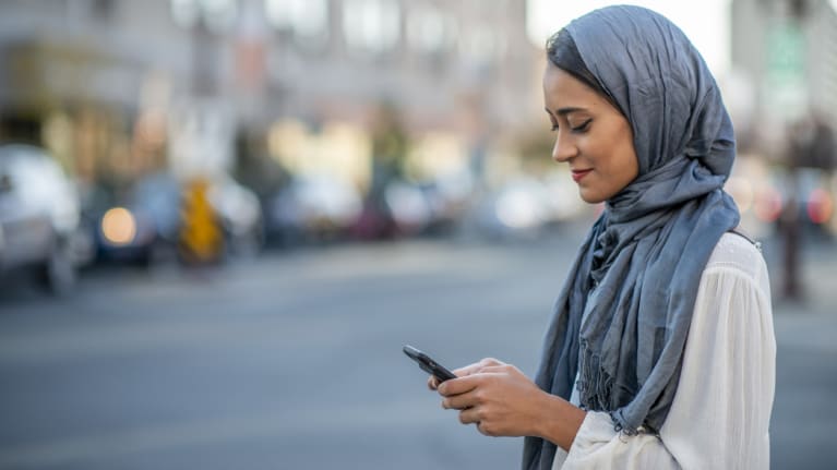 a woman wearing a headscarf checks her cellphone