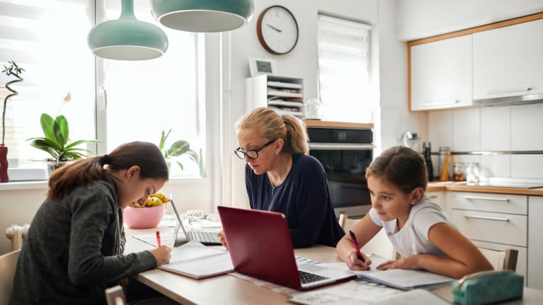 mother working remotely helping two kids with school work